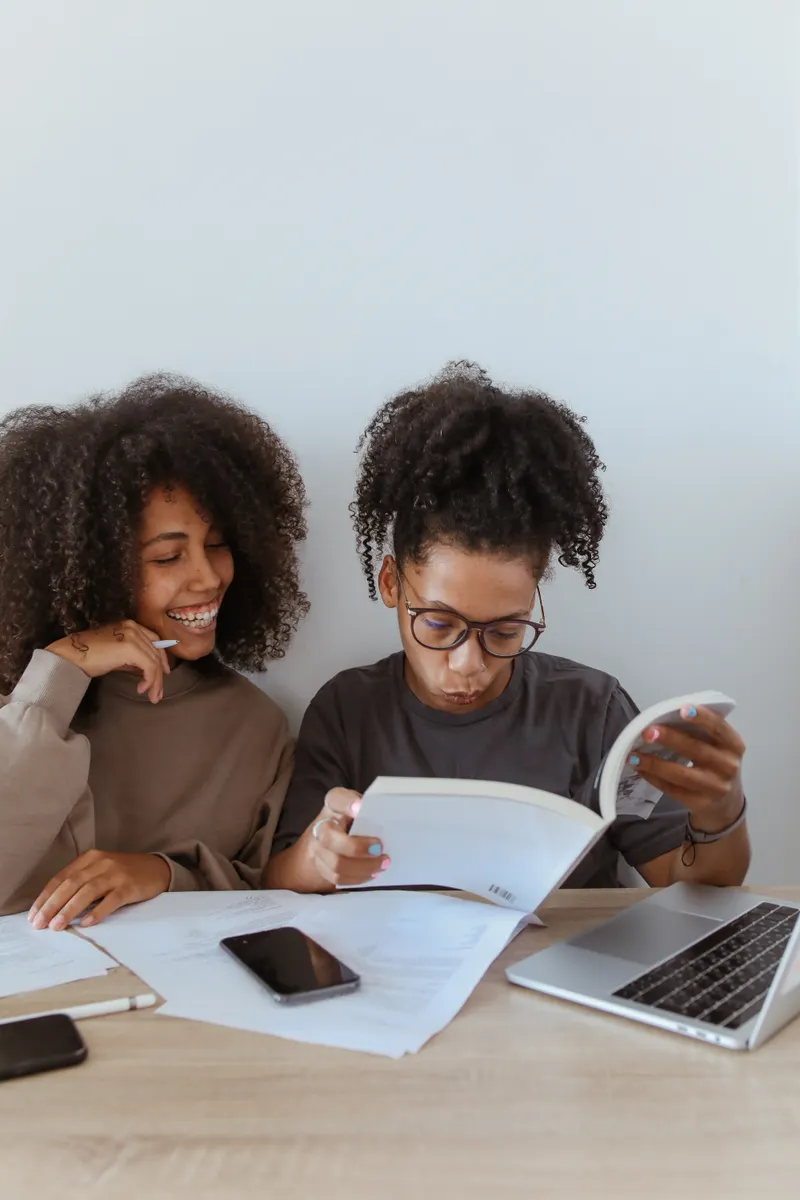 Deux étudiantes lisant et échangeant à côté de leur ordinateur — photo d’illustration
