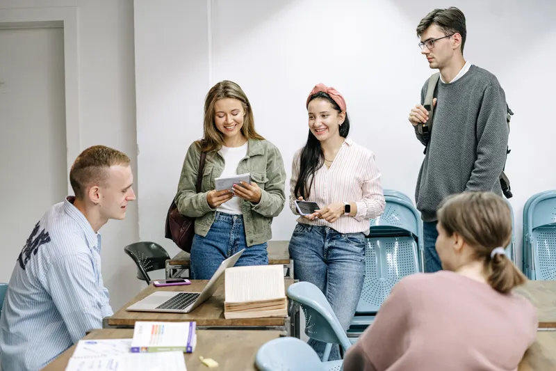 Étudiants échangeant autour de livres et d’un ordinateur — photo d’illustration